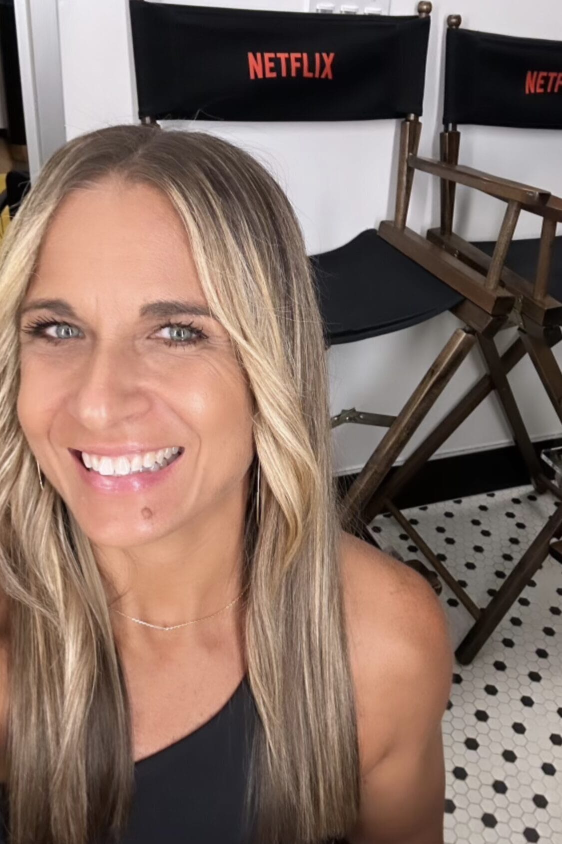 alycia smiling in front of a couple of directors chairs with the netflix logo in her green room